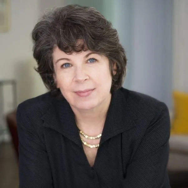 A woman in black shirt and necklace sitting down.